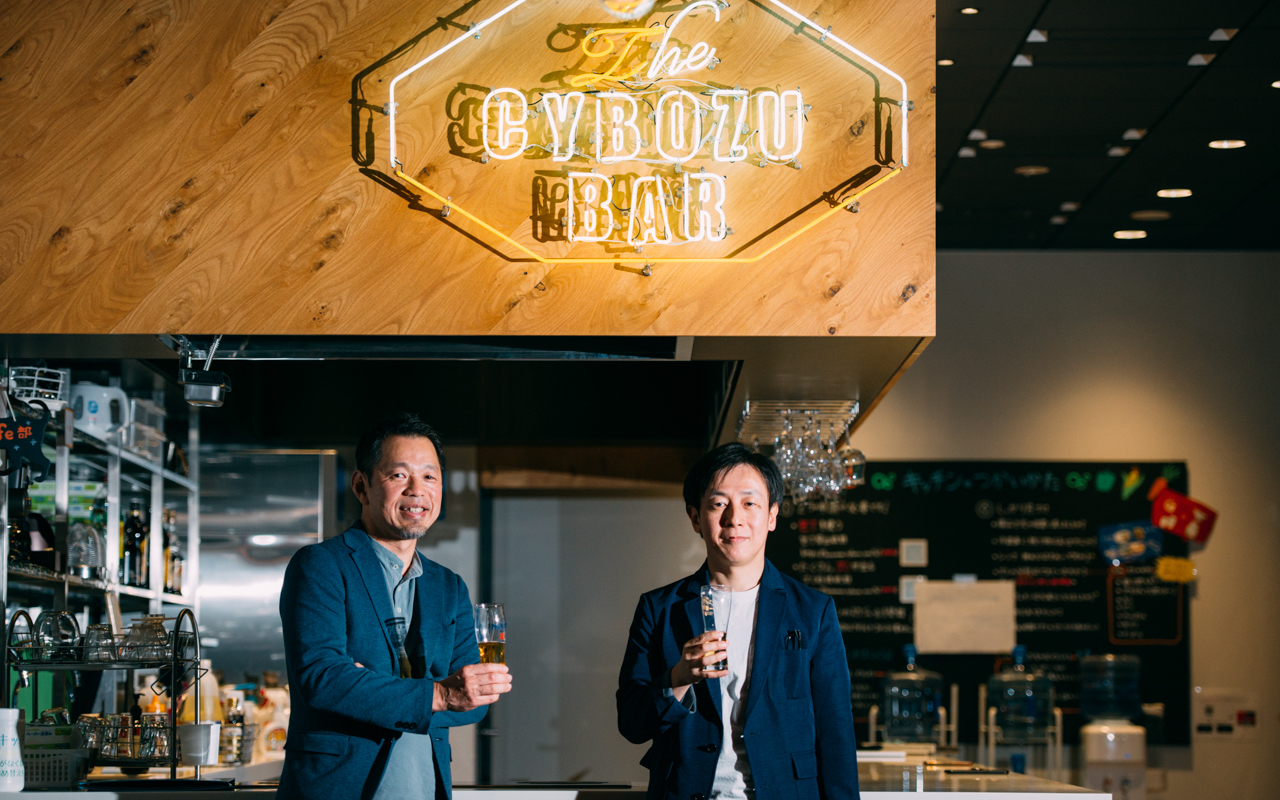 Cybozu CEO Yoshihisa Aono and president Osamu Yamada standing in front of the Cybozu Bar