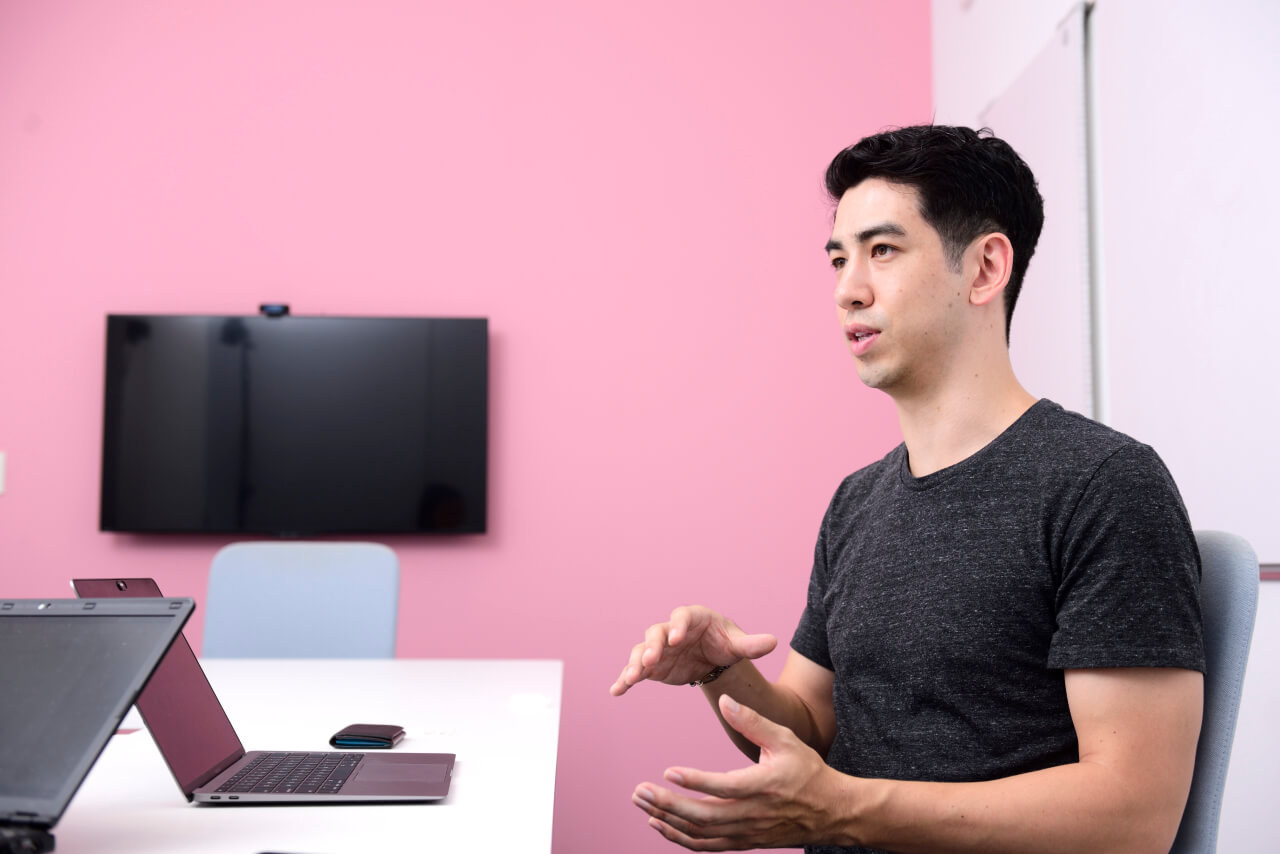 Phillip in a pink meeting room explaining Plug and Play's values