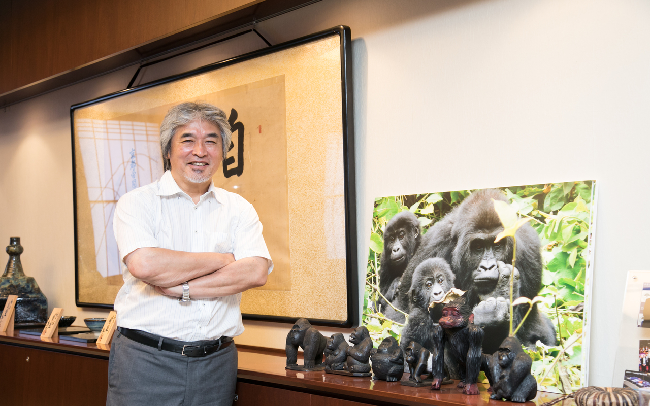 Professor Juichi standing next to a picture of gorillas