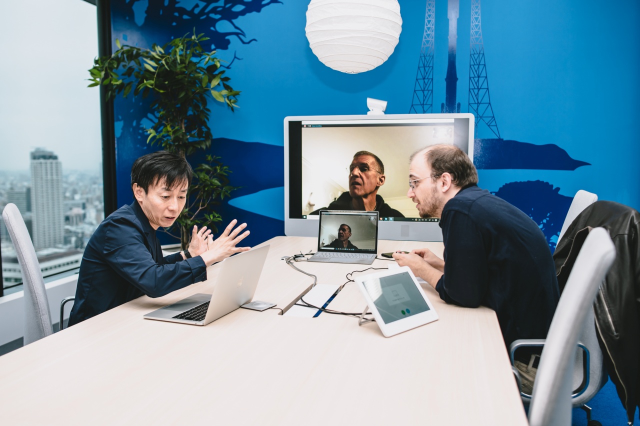 Yoshihisa Aono making a point while reading his notes during the videoconference