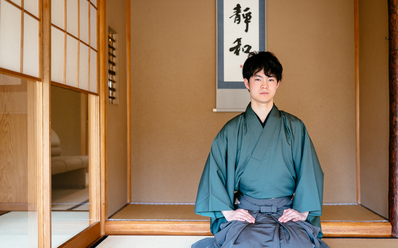 Tea master Ryo Iwamoto sitting with his legs folded in traditional Japanese style, in a Japanese tea house