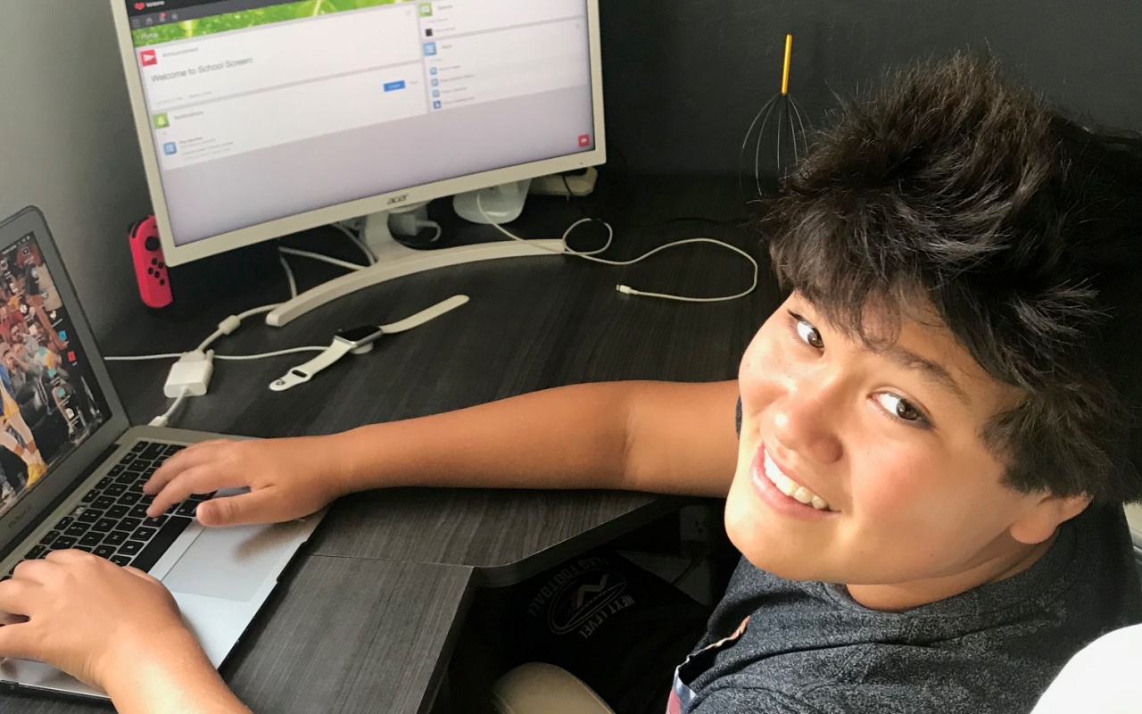 13-year old Taeden, sitting at his computer and smiling