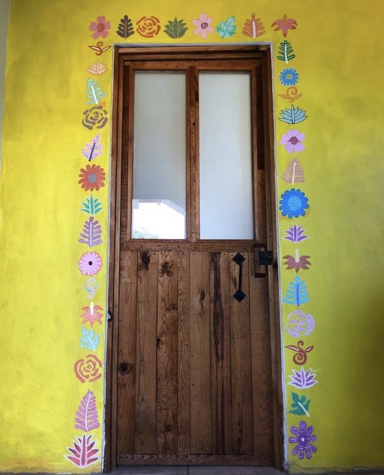 The wall around a door is decorated with floral and sun motifs