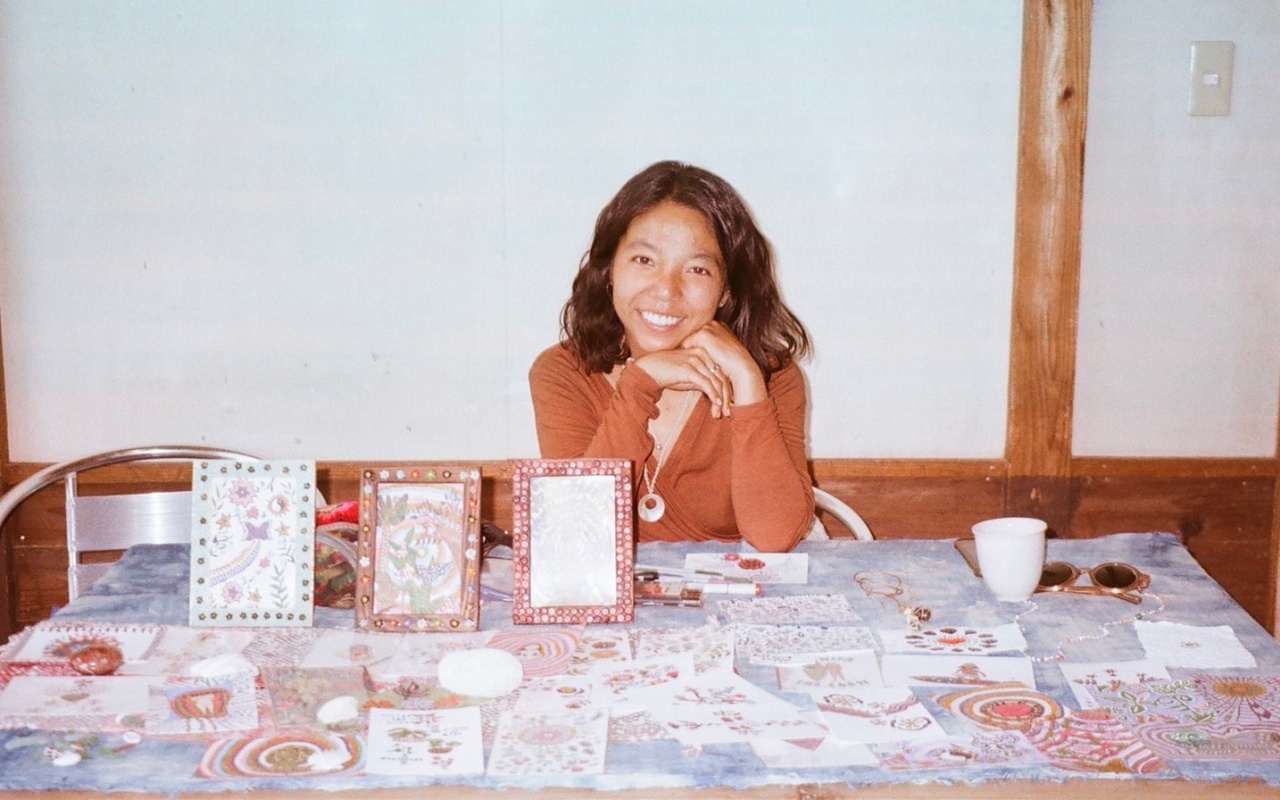 Miori Hase sitting behind a desk full of her illustrations